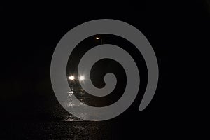 A minimal picture of car headlights underneath a street light on a dark rainy night