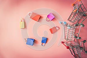 Minimal shopping online concept, Colorful paper shopping bag and trolley go down from floating pink background