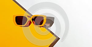 Minimal style composition made of sunglasses on orange and white sunlit background