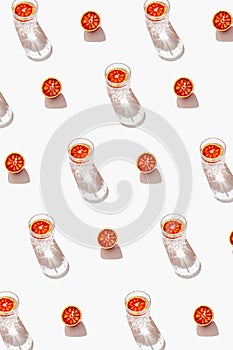 Minimal style creative pattern made of half blood red orange and two glasses with cocktail on white background with shadow. Summer