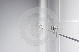 Minimal white closet or wardrobe with silver door handles. Close-up and selective focus at the knob handle.