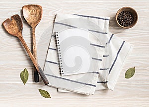 Minimal white kitchen background with blank notebook for text, cotton napkin, various spices and wood appliances