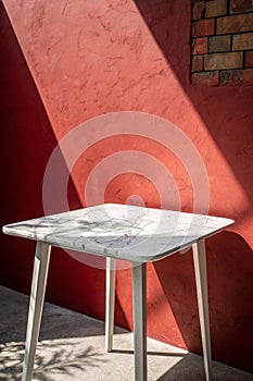 Minimal White Marble Table Corner with Light Beam, Shadow, and Spotlight on the Red Concrete Wall Background, Suitable for Product