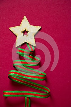 Minimal winter creative table flat lay, Christmas tree made of ribbon and wooden star and gift figurines