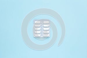 Minimalism. Packaging of white capsules with medicine, on a blue background. Painkiller. Medicine concept. Copy space.