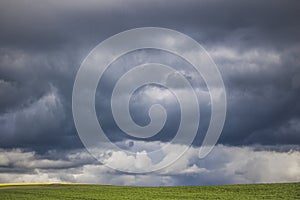 Minimalism photo of a dramatic clouds over a green field.