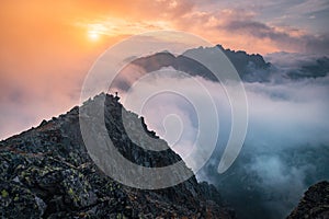 Minimalism photo, hiker at the top of the hill. Fog in the mountains valley. Autumn nature, sunset light in background