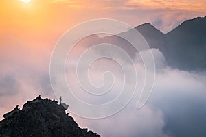 Minimalistická fotografie, turista na vrcholu kopce. Mlha v údolí hor. Podzimní příroda, západ slunce světlo v pozadí