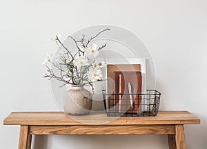 Minimalism style living room interior. Flower arrangement, metal basket with magazines on an oak wooden table