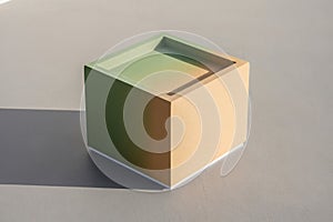 Minimalist beige cube with a subtle shadow on a neutral gray surface