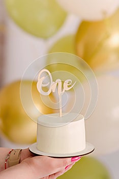 Minimalist cake with balloons in the background for the baby's first birthday