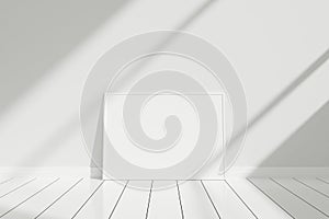Minimalist and clean horizontal white poster or photo frame mockup on the floor leaning against the room wall with shadow