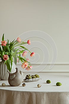 Minimalist composition of easter dining room interior with copy space, vase with tulips, colorful eggs, gray hen sculpture, beige