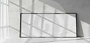 Blank picture frame leaning against a wall with dramatic sunlight and shadow patterns