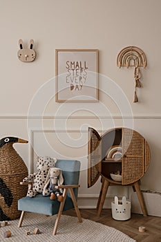 Minimalist composition of kid room interior with mock up poster frame blue armchair, plush toys, wooden blocks, rattan sideboard,