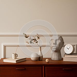 Minimalist composition of living room interior with copy space, wooden sideboard, vase with dried flowers, gray sculpture, books,