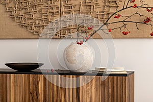 Minimalist composition of living room interior with mock up poster frame, wooden sideboard beige vase with rowan, black bowl,
