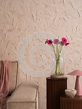 Minimalist composition of living room interior with modular sofa, wooden sideboard, glass vase with pink flowers, lamp, casket,