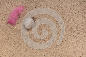 Minimalist composition in zen style, mindfulness. Copy space. Delicate pink feather on the beach, sand