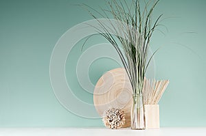 Minimalist cozy interior with beige natural organic home decor - bamboo plate, bouquet of herb in bottle, round sheaf of twigs.