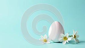 Minimalist Easter composition with white egg and delicate white flowers on pastel blue background with copy space