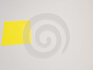 Yellow sticky note on a white wall background