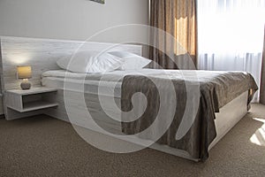 Minimalist interior of the bedroom with a double bed on the wooden floor, CURTAINS ON the WINDOW, sunlight. home interior.