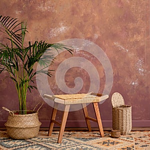 Minimalist interior of boho dining room with copy space, rattan stool, basket with plant. and personal accessories. Brown wall.