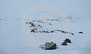 Minimalist Norwegian landscape of dark rock outcrops on snow-covered hill