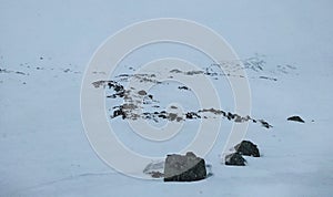 Minimalist Norwegian landscape of dark rock outcrops on snow-covered hill photo