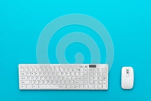 Minimalist photo of computer keyboard and mouse on turquoise blue