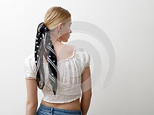 Minimalist photo, Fashionable girl in stylish summer things . View from the back. Earrings, a ring , a scarf on her head