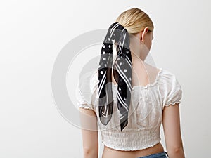 Minimalist photo, Fashionable girl in stylish summer things . View from the back. Earrings, a ring , a scarf on her head