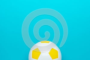 Minimalist photo of soccer ball over turquoise blue background with copy space