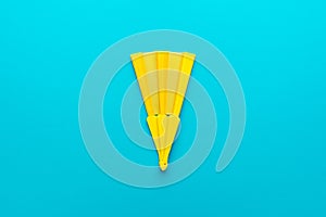 Minimalist photo of yellow hand fan on turquoise blue background with copy space