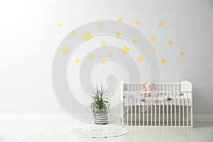 Minimalist room with baby crib and decor elements. Space for text