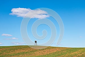 Minimalist spring landscape with field and hunting hide