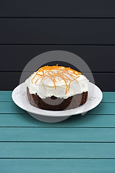 Minimalist style pastry. Homemade traditional fruit cake with cream icing and orange peel on blue background copyspace