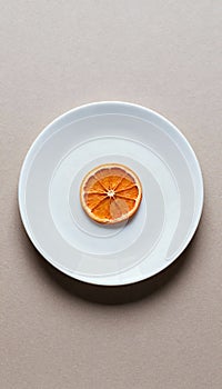 Minimalist white plate with single dried orange slice centered, simplicity and focus concept