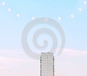 Minimalistic abstract surreal photoshopped photo of architecture. Concrete soviet house with a necklace of moons above photo