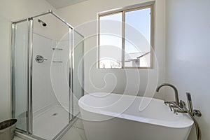 Minimalistic bathroom interior design in white color with a bathtub and shower cabin