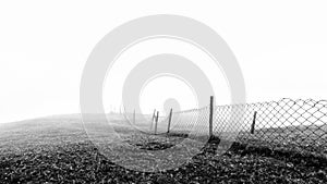 Minimalistic black and white background of a wired fence in foggy and misty weather condition