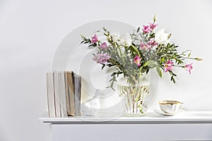 A minimalistic bouquet of white tulips, pink eustoma, hyacinth, eucalyptus in a fluted glass vase on a white panel of an