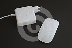 Minimalistic combination of white mouse and charger for laptop