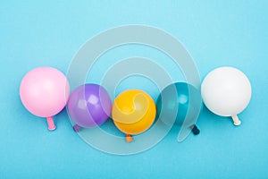 Minimalistic composition with colorful balloons on blue table top view. Birthday or party background. Flat lay style.