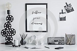 Minimalistic composition of creative hipster room interior with mockup poster frame, creative design lamp and office accessories.