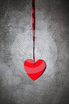 Minimalistic decoration, red heart over textured grey background