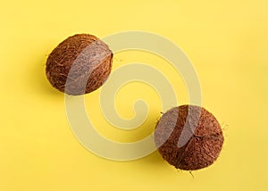 Minimalistic flat lay with coconuts on yellow background. Top View. Pop art design, creative summer pattern.