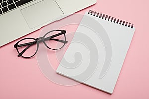 Minimalistic flat lay composition of laptop, glasses and jotter