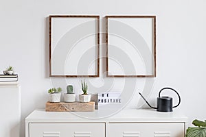 Minimalistic home decor of interior with two brown wooden mock up photo frames on the white shelf with books, beautiful plants.